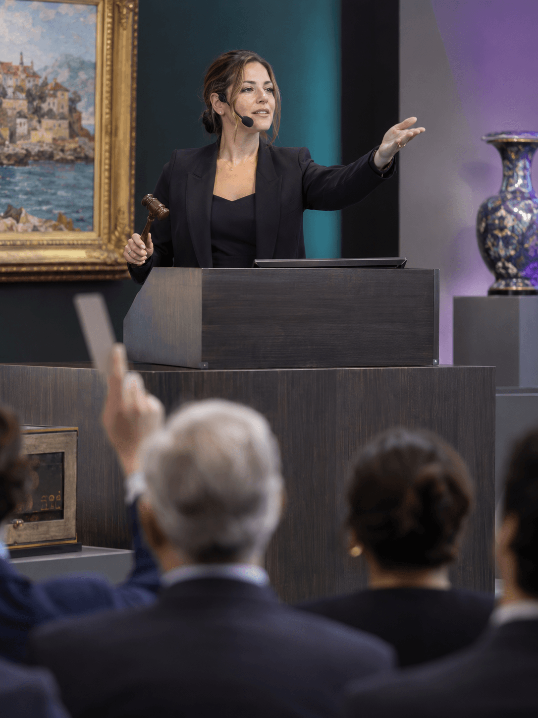 A female auction manager with headset directing a sale from a contemporary auction rostrum