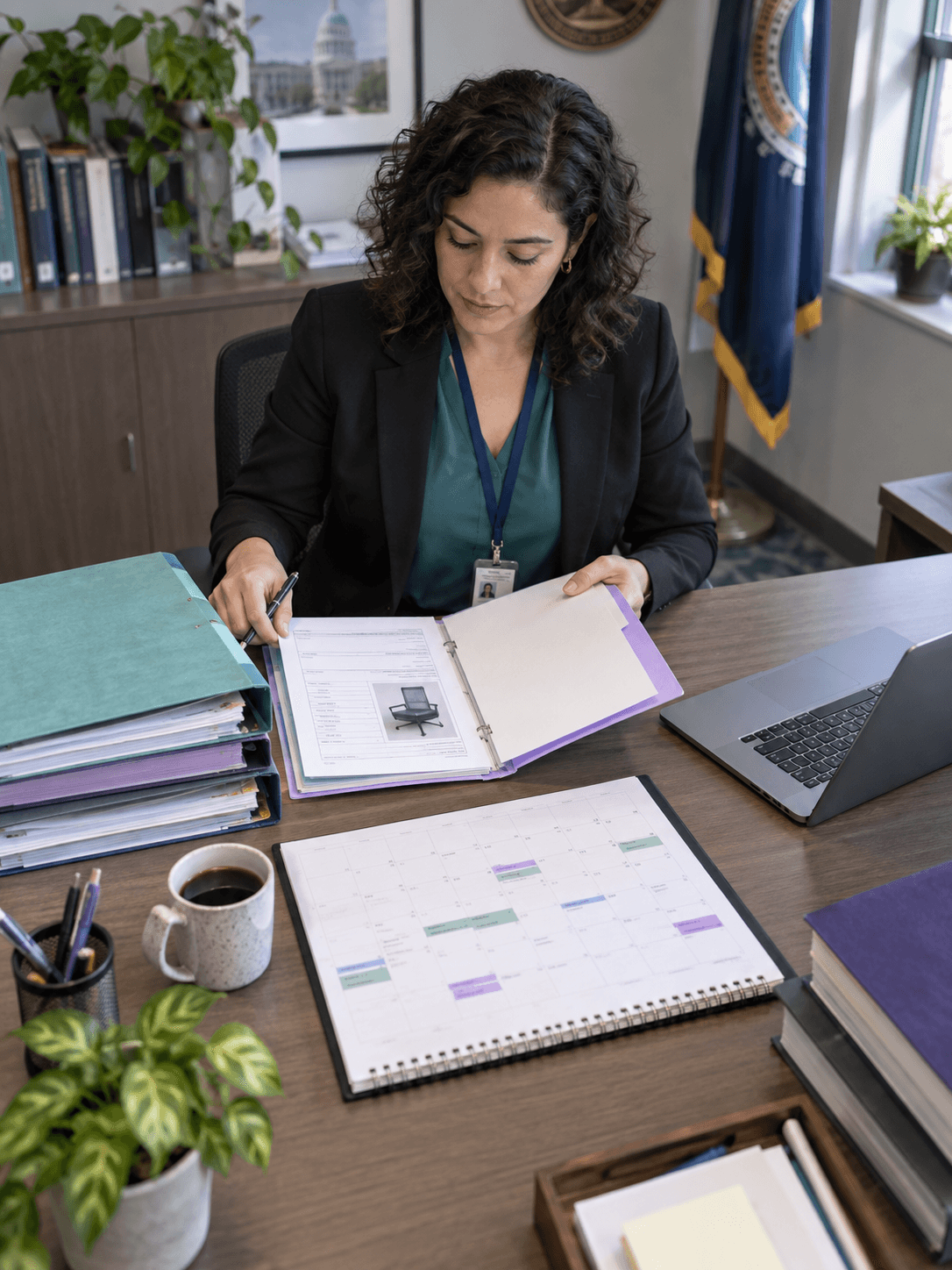 Overhead view of a public disposal planner organizing approval folders, auction timetable and laptop on a neat civic office desk
